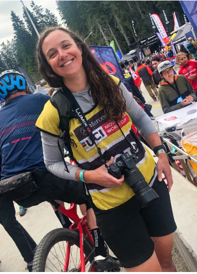 Elisabeth Reinkordt wearing UCI press credentials and holding a long lens camera at a World Cup mountain bike race
